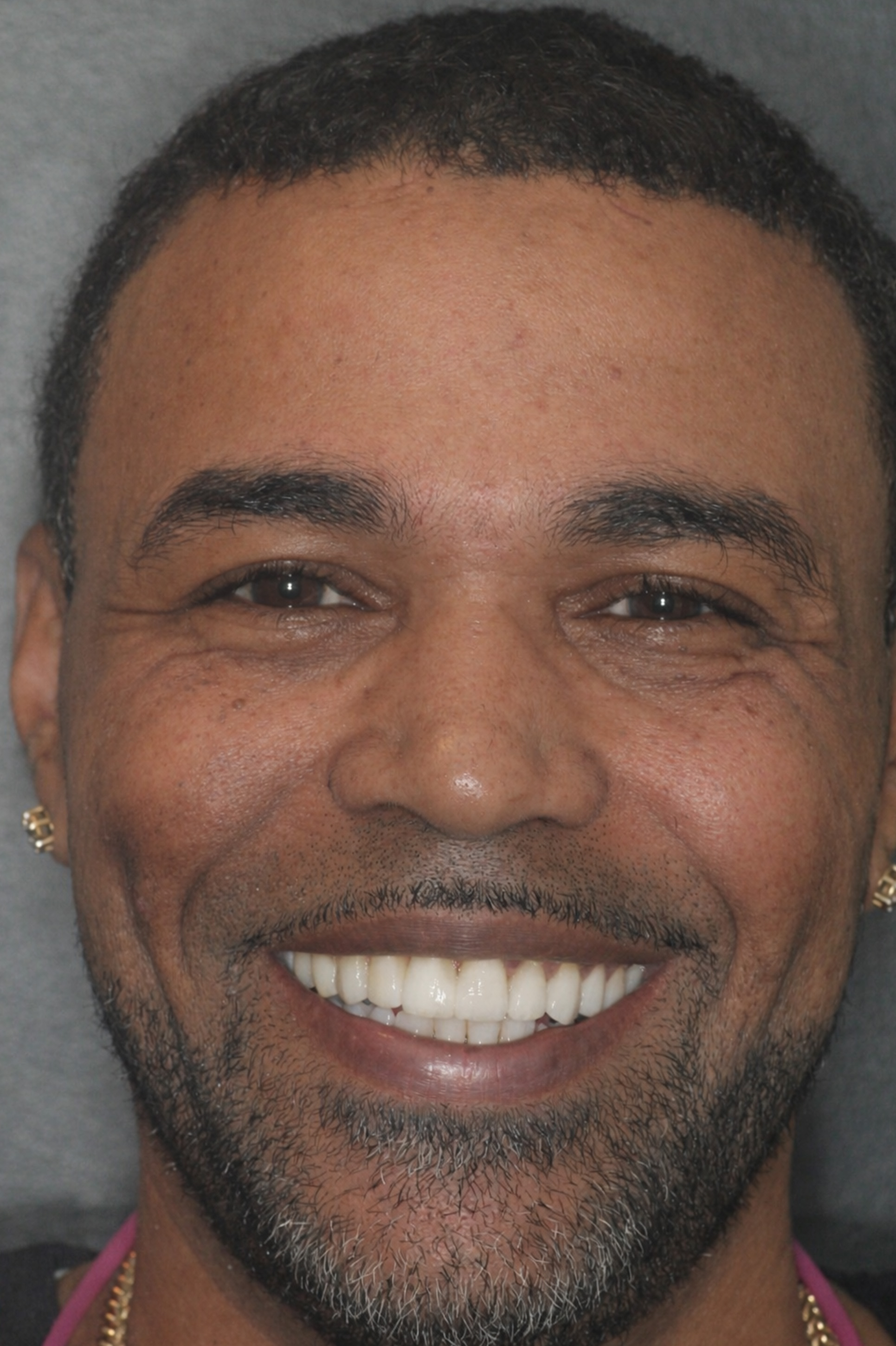 The image shows a man with a beard smiling at the camera against a neutral background.